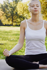 Girl meditates while practicing yoga outdoors in park