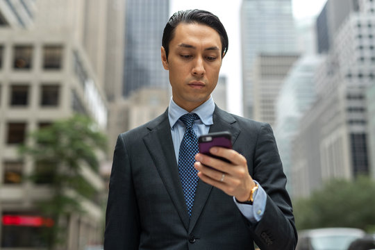 Asian businessman in city walking using cell phone