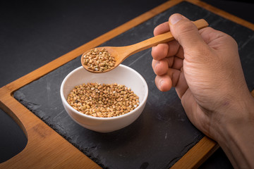 Man hand holding spoon with organic buckwheat