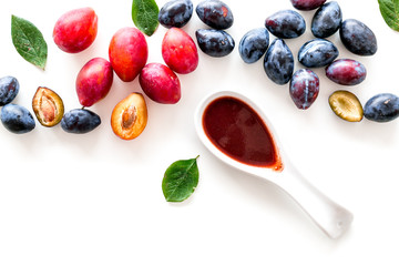 Fresh tkemali sauce. Traditional caucasian, georgian sauce or plum jam in spoon near plums on white background top view space for text