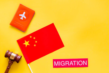 Immigration to China concept. Text innigration near passport cover and chinese flag, judge hammer on yellow background top view copy space
