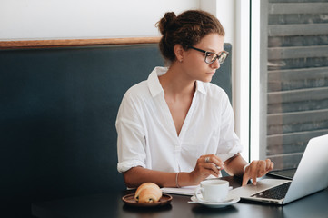 Young beautiful woman with laptop sitting in cafe and working with laptop