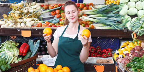 seller woman is demonstraiting oranges