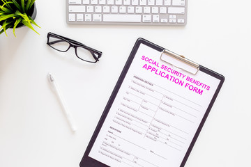 Social security benefits. Application form near pen and glasses on white background top view