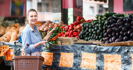 Portrait of woman who is choosing pepper in the market.