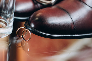Men's shoes,   engagement rings on a glass chair. Wedding details 