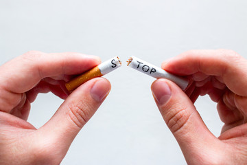 smoker breaks a cigarette with the word stop. concept stop smoking on white background