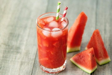 Watermelon smoothie in jars with fresh watermelon slices on gray wooden background