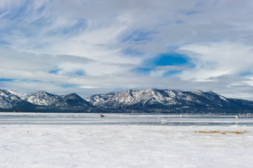 Fototapeta na wymiar Beach lake in the mountains on winter with snow cover.