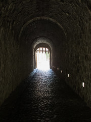 A light in the end of a tunnel. Medieval gate in the old castle. The light in the darkness.