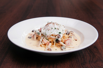 Italian pasta spaghetti with creamy alfredo sauce, mushroom and poached egg