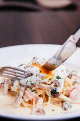 Italian pasta spaghetti with creamy alfredo sauce, mushroom and poached egg