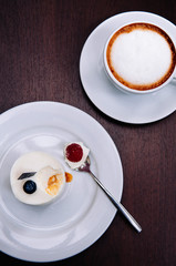 Creamy cheesecake with raspberry and blueberry on white dish and cappucino coffee cup in bekery cafe