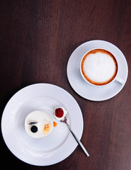 Creamy cheesecake with raspberry and blueberry on white dish and cappucino coffee cup in bekery cafe