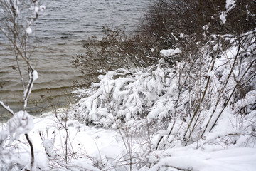 Snowy river bank. Winter river. A winter river landscape with snow-covered banks.