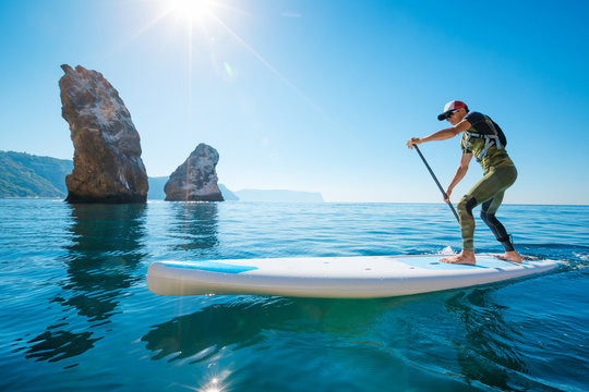 Stand up paddle boarding. Young man floating on a SUP board. The adventure of the sea with blue water on a surfing.