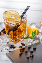 A glass of whiskey with ice on white wooden background
