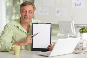 Portrait of mature businessman working at table with laptop at home