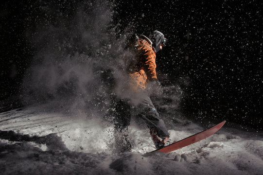 Male snowboarder riding on board on a powder snow