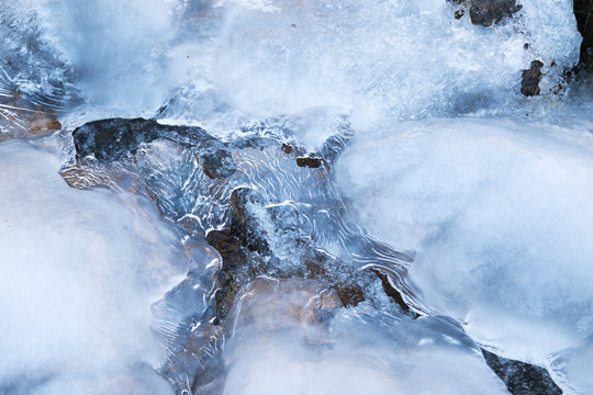 Surface of a frozen winter brook covered with ice..