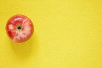 Red fresh apple on a yellow background. Close-up, copy space