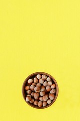 bowl with hazelnut on a yellow background. Healthy eating. Close-up, copy space, view from above. Unpeeled walnut.