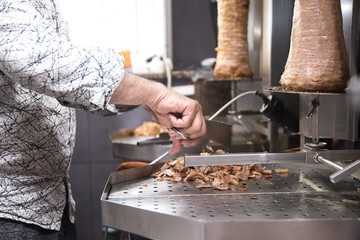Cocinero cortando rollo de kebab - obrazy, fototapety, plakaty