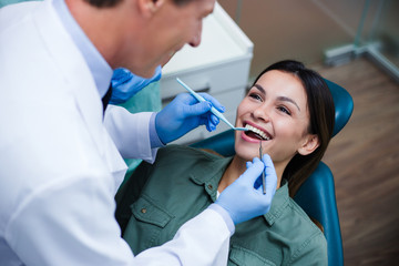 Amazing smile! Top view of dentist examining his beautiful patient in dentist’s office