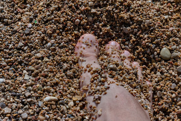 Foot in the small pebbles on the beach