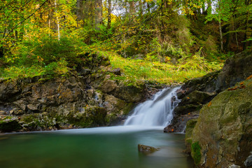Small waterfall in the colourful autumn forest and beautiful light