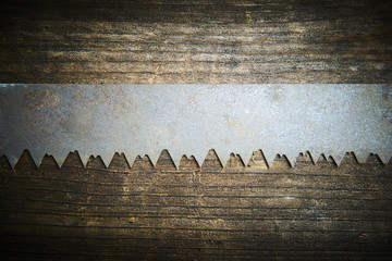 Close up of an old and rusty antique handsaw om wooden desk. Selective focus