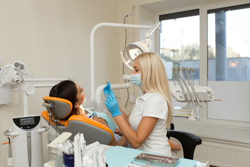 Pretty girl having mouth checkup in hospital by professional female dentist