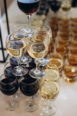 Many glasses with white and red wine on buffet table.
