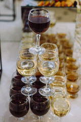Many glasses with white and red wine on buffet table.