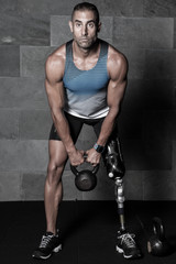 Fototapeta na wymiar Sportive man with prosthesis training with kettlebell