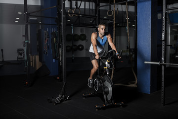 Obraz na płótnie Canvas Sportsman riding stationary bicycle in gym