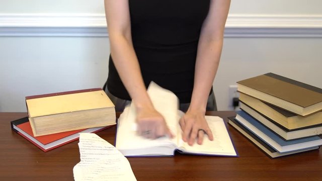 Angry woman destroying book by tearing out pages