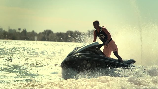 Active man on jet ski having fun on river in slow motion. Young sportsman riding jet ski at sunset. Male rider have fun on water waves