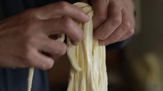 Video clip. A woman weaves a pigtail of cheese. Chechil homemade cheese production. Modern Russian village. Russian farmers.