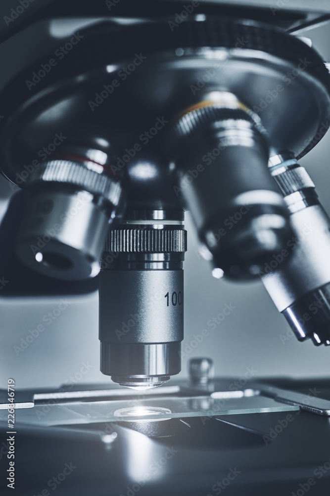 Wall mural close-up shot of modern microscope with sample slide at laboratory.