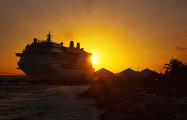 Cruise ship docked at tropical port on sunset. 