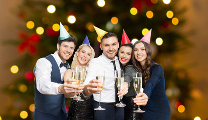 celebration, party and holidays concept - happy friends with champagne glasses over christmas tree lights background