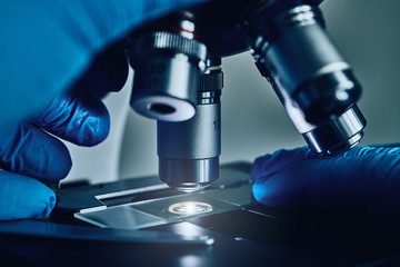 Scientist hands with sample slide on microscope close-up shot in the laboratory