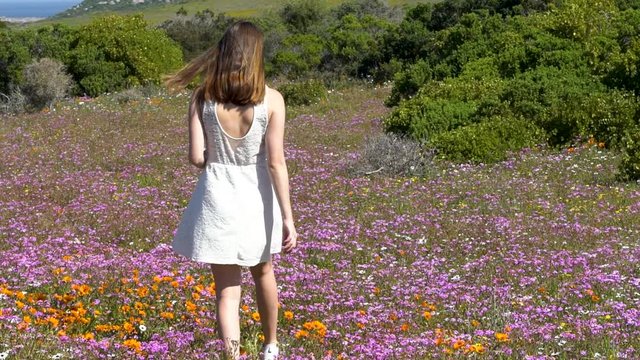 Wide shot of girl walking between flowers