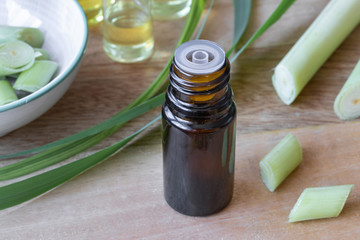 A bottle of lemon grass essential oil with fresh lemon grass