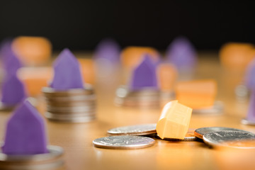 SMALL PLASTIC HOUSE  COLLAPSES FROM STACKED MONEY COINS, BUSINESS AND FINANCIAL CONCEPT