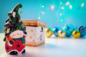 Bright toy dwarf with a cheerful face and a bell on the cap shiny balls, box on white background.