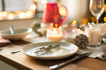 christmas, holidays and table setting concept - plate decorated with fir branch for festive dinner at home