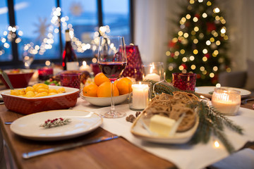 christmas dinner and eating concept - glass of red wine and food on table at home