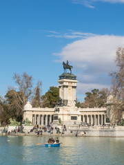 Fototapeta na wymiar Beautiful picture of tourists on boats at Monument to Alfonso XII in the Parque del Buen Retiro. in Madrid, Spain